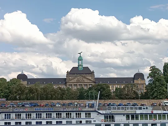 Historisches Gebäude mit Uhrturm, bewölkter Himmel.