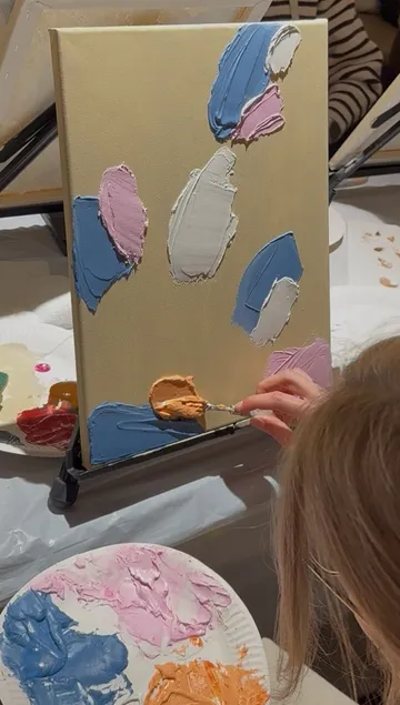 Person using knife to paint on canvas.