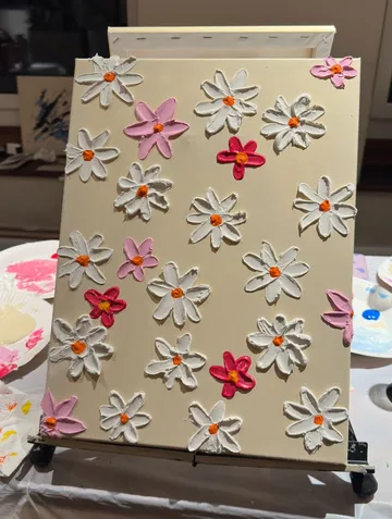 Canvas with textured flowers on easel.