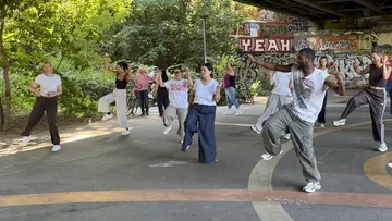 Gruppe tanzt im Park mit Graffiti.