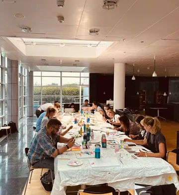 People painting at a long table indoors.