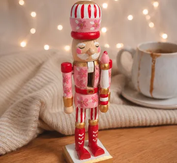 Rosa Nussknacker steht neben Kaffeetasse.