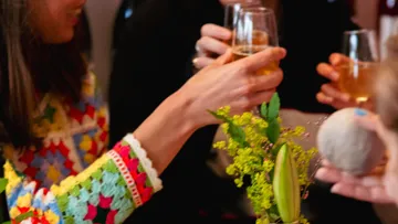 People toasting with drinks around flowers.