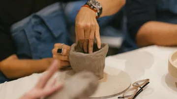 Hände formen Ton auf einem Tisch.