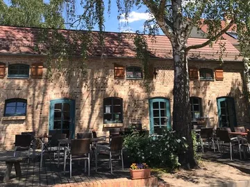 A building with tables stands outside under trees.