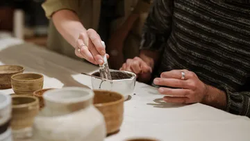 Hands painting pottery on a table.