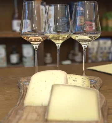 Cheese and wine glasses on a wooden board.
