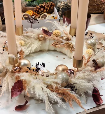 Decorative wreath with candles on table.