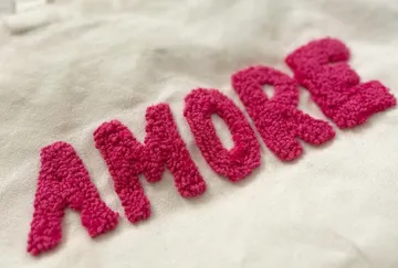 Pink embroidered text on beige fabric.
