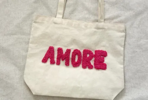 Stofftasche mit 'AMORE' in pinken Buchstaben.