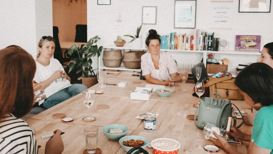 A group of women sit around a table and talk.