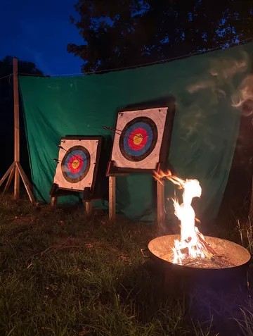 Archery targets at night with fire nearby.