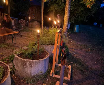 Fackeln beleuchten Bögen neben Terrasse und Garten.
