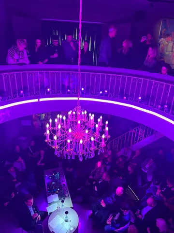 Kronleuchter beleuchtet eine volle Nachtclub-Szene.
