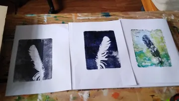 Three feather prints on a wooden table.
