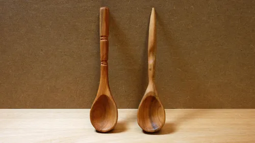Two wooden spoons on a wooden surface.
