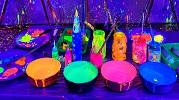Glowing paints on table under blacklight.