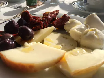 Käse, Oliven und getrocknete Tomaten auf einem Teller.
