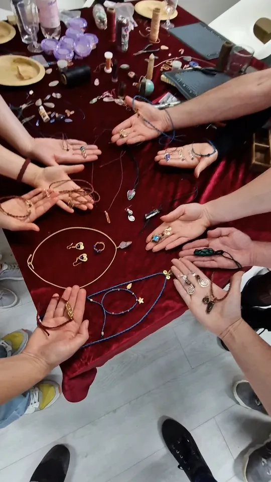 Hände präsentieren handgefertigten Schmuck auf Tisch.