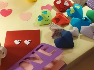 Colorful heart-shaped crafts on yellow surface.