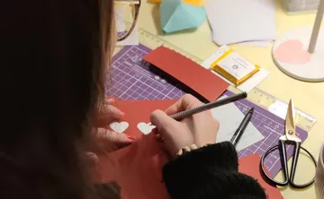 Person crafting paper hearts at desk.