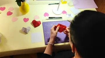 Person folding origami heart on table.