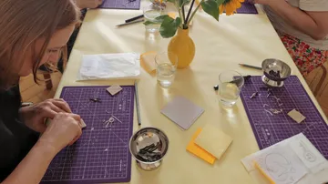 People crafting at a table, sunflower centerpiece.