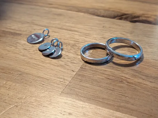 Zwei Ringe und Anhänger auf Holztisch.