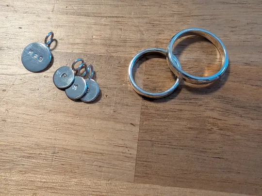 Silberne Anhänger und Ringe auf Holzboden.