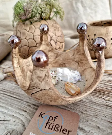 Ceramic crown-shaped bowl with sea shells, rustic decor.