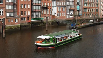 Touristenboot fährt am Kanal neben historischen Gebäuden.