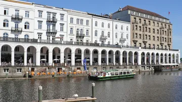 Weißes Gebäude mit Bögen neben einem Kanal.