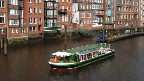 Tour boat sailing along brick buildings.