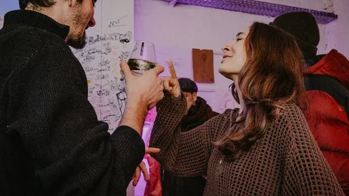 People conversing with drinks in art-filled room.