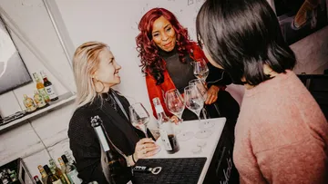 Three women talking at a bar counter.