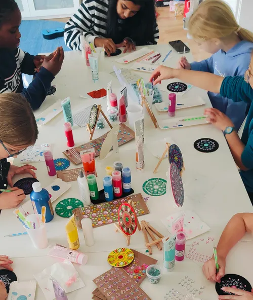 Children painting mandalas at a table.
