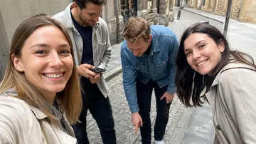 Gruppe macht Selfie auf Kopfsteinpflasterstraße.