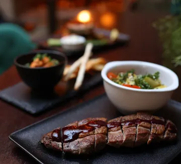 Sliced steak with sauce, vegetables, indoors.