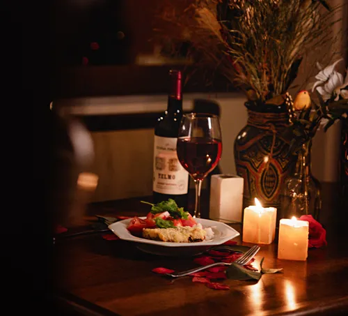 Dinner table with wine, candles, platter.