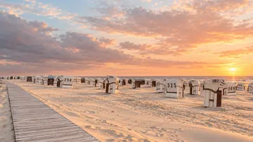 Beach chairs facing ocean at sunset.