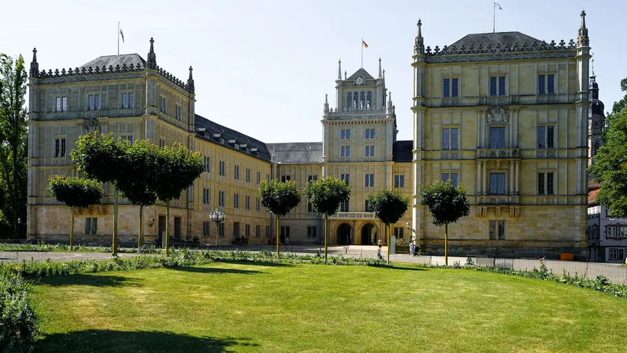 Großes Schloss steht inmitten gepflegten Gartens.