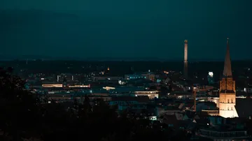 Stadtbild bei Nacht mit beleuchteten Gebäuden.