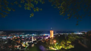 City skyline with illuminated tower at night.