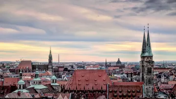 Stadtansicht mit historischen Gebäuden, bewölkter Himmel.