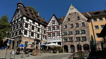 Historic half-timbered buildings in a sunny plaza.