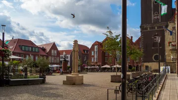 Platz mit Denkmal, Gebäuden, klarem Himmel.