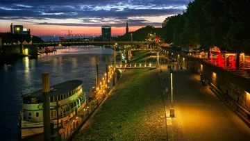Flusspromenade mit Boot bei Sonnenuntergang