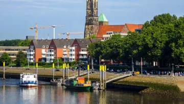 Boote am Flussufer mit Stadtansicht.