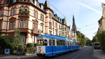 Blue tram travels past historic buildings.