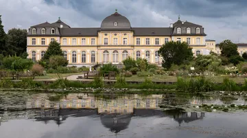 Historic building with cloudy sky reflection on pond.